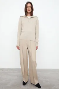 Detailed texture of oatmeal knit sweater with half-zip collar and ribbed cuffs
