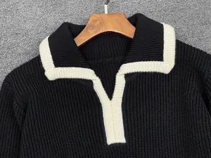 Detail of black polo collar knit sweater with white contrast piping and thick texture