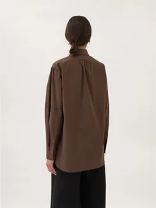 Vista posteriore dettagliata di una camicia in cotone marrone scuro con dettaglio a pieghe
