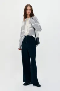 Detail of geometric pattern blouse with loose wide leg pants and chic leather crossbody bag