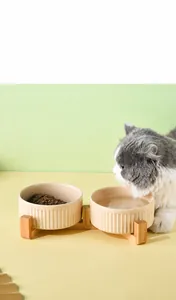 Close-up of dual ceramic pet bowls with sesame glaze on a natural wooden stand