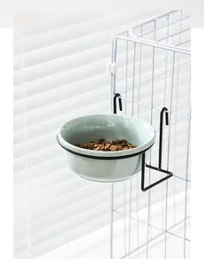Close-up of hanging pet bowl with green ceramic basin and black metal wire cage mount
