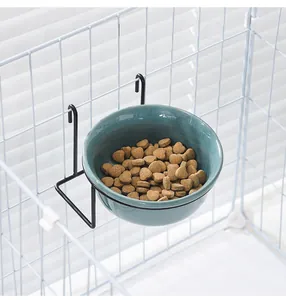 Detail of hanging ceramic pet bowl in cyan with black metal rack installed on cage