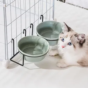 Hanging double ceramic pet bowls with black metal rack on a white cage for cats