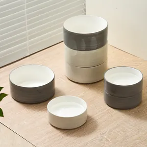 Stackable ceramic pet bowls in neutral tones on a modern wooden table setting