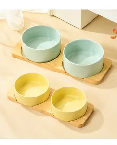 Detailed view of ceramic pet bowls in green and yellow with bamboo non-slip stands
