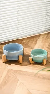 Detail of ceramic pet bowls on wooden stand with curved surface for easy feeding