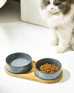 Detailed view of dual ceramic pet bowls set in an oval solid wood non-slip tray base