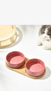 Dual pink ceramic pet bowls on a wooden stand for cats with a non-slip elevated base