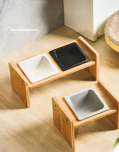 Close-up of ceramic cat bowls on elevated bamboo stands with an ergonomic tilted design