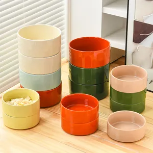 Minimalistische keramische voerbakken in diverse kleuren op een houten tafel