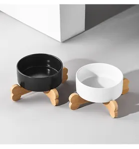 Detail of matte ceramic cat bowls in black and white with a wooden bone-shaped stand