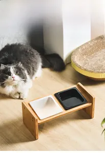 Detail of raised bamboo pet feeder stand with ceramic cat bowls and a cat model