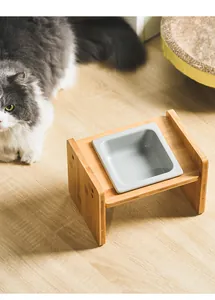 Detail of square ceramic cat bowl on elevated wooden stand with ergonomic tilted design