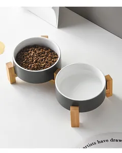 Detail view of double ceramic pet bowls on a bamboo stand with dry food and water
