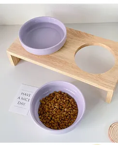 Detail of elevated wooden pet feeder with two purple ceramic bowls and dry food