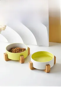 Detail view of dual ceramic pet bowls in white and yellow with a natural wooden stand