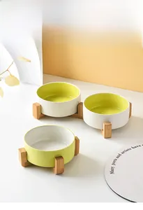 Close-up of matte ceramic pet bowl with yellow interior and bamboo wooden stand base