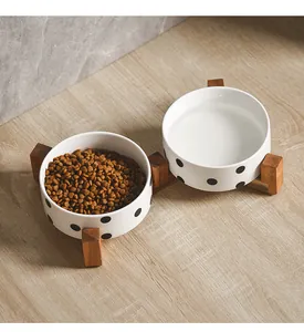 Detail of ceramic cat bowls with black polka dots on a minimalist wooden stand