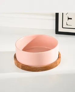 Pink ceramic pet bowl with wooden base featuring a wide mouth for comfortable eating