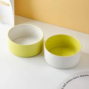 Minimalist bicolor ceramic cat bowls with yellow and white finish on a wooden stand