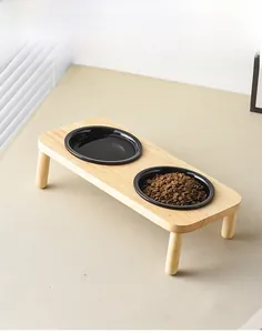 Macro detail of tilted wooden pet feeder stand with two black ceramic bowls for cats