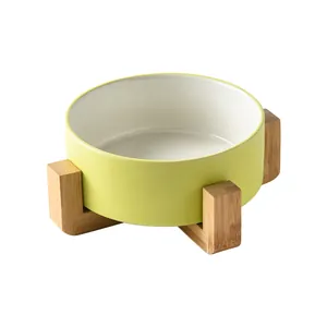 Minimalist ceramic pet bowl with light yellow matte exterior and wooden elevated stand
