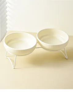 Detalle de cuencos dobles de cerámica crema con soporte de metal blanco para mascotas