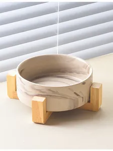 Detail eines Keramik-Napfs mit Marmormuster und minimalistischem Holzkreuzständer