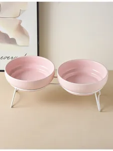 Detalle de dos cuencos ceramicos rosas con soporte de metal blanco para mascotas