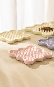 Detail of flower-shaped ceramic pet slow feeder bowls in soft pink, purple, and beige
