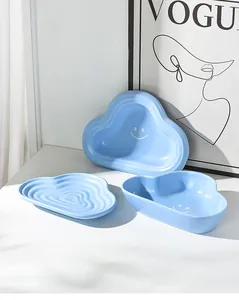 Detail of sky blue cloud-shaped ceramic pet bowls featuring minimalist white smiley faces