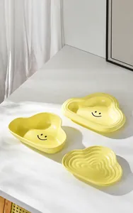 Close-up of matte yellow cloud-shaped ceramic bowls with smooth glaze texture and smiling faces