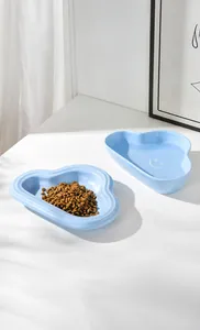 Detail of light blue cloud-shaped ceramic pet bowls with kibble and water on white surface