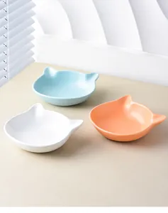 Detailed view of three cat-shaped ceramic bowls in white, sky blue, and light orange