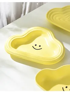 Close-up of cloud-shaped bright yellow ceramic pet bowl with a cute black smiley face