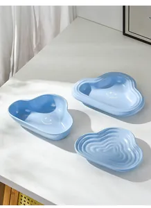 Detail of cloud-shaped ceramic pet bowls in light blue with smiling face and wave pattern