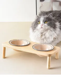Detalle de cuencos dobles elevados de cerámica con soporte de madera natural para gatos