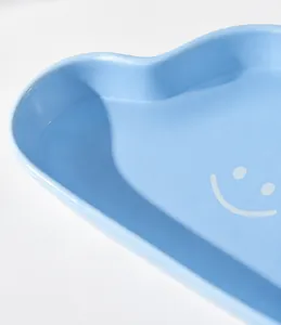 Detail display of light blue heart-shaped ceramic pet bowl with a white smiley face