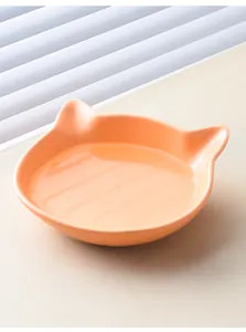 Detail of a cat-ear shaped ceramic bowl in light orange with water, macro indoor view