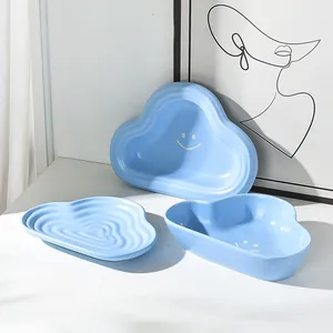 Cloud-shaped light blue ceramic pet bowl set with smiley face design on white table