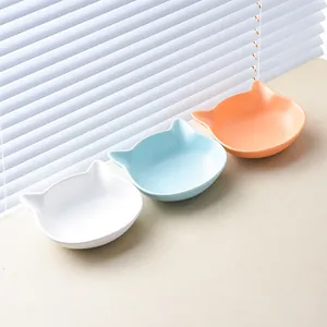 Three minimalist cat-ear ceramic bowls in pastel blue, orange, and white for pets