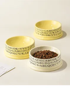 Close-up of ceramic volcano-style pet bowls with decorative text and dry food