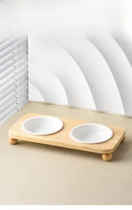 Dual white ceramic pet bowls on a minimalist light wood stand with rounded legs