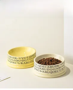 Close-up of ceramic pet bowls with letter print, showing smooth glaze and wide mouth design