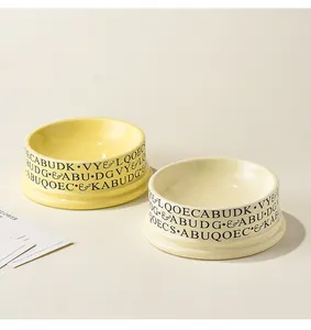 Detail of yellow and cream ceramic pet bowls with modern black typography print