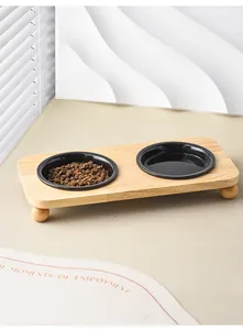 Detail of wooden pet bowl stand with ball-shaped feet and two black ceramic bowls