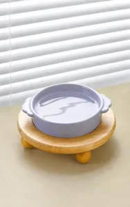 Detalle de cuenco cerámico lila para mascotas con soporte de madera y asas laterales