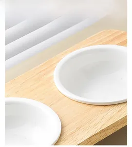 Close-up of dual white ceramic pet bowls set in a natural wooden stand for cats