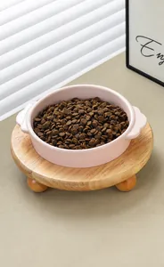 Detalle del cuenco cerámico rosa para gatos con bordes ondulados y soporte de madera elevado